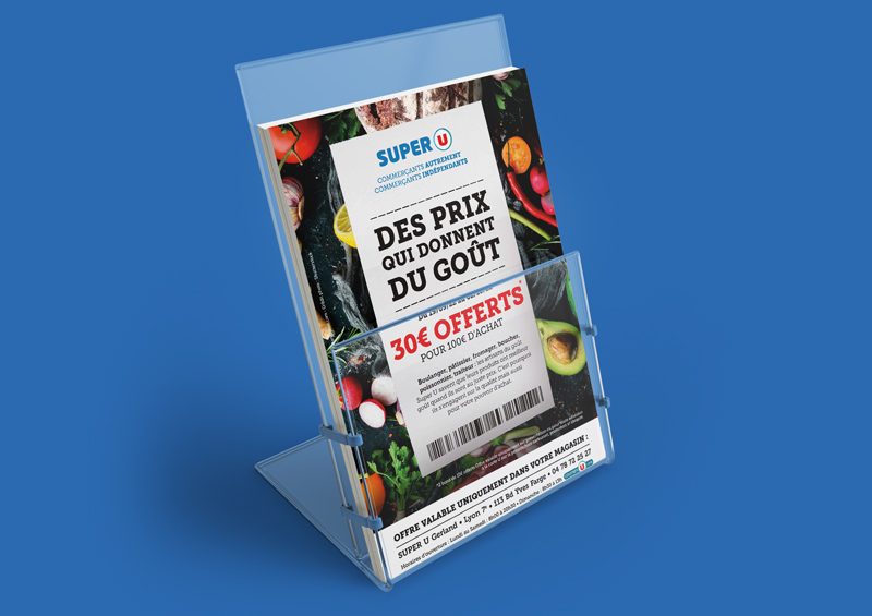 Le flyer pour la promotion en cours chez Super U présente un fond avec une photographie de fruits et légumes, incluant des agrumes, des avocats, des poivrons et des tomates. Au centre du flyer se trouve un ticket de caisse de Super U avec un message promotionnel indiquant que les clients pourront bénéficier de 30 € de réduction pour chaque achat de 100 € ou plus effectué entre le 19 septembre 2022 et le 2 octobre 2022 au Super U de Gerland, situé dans le 7ème arrondissement de Lyon.