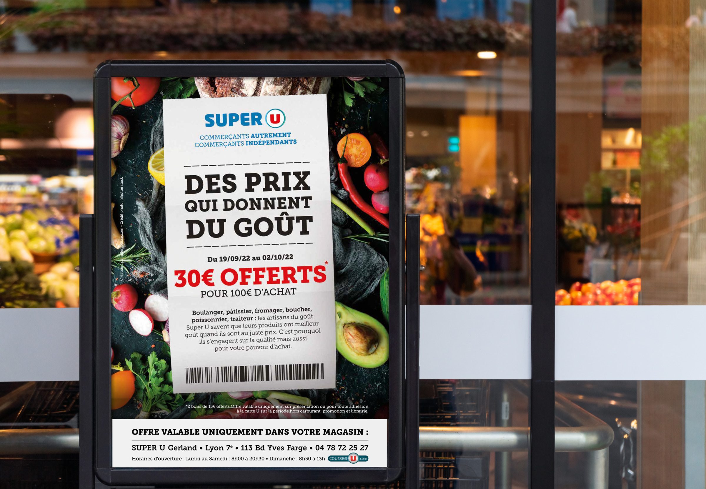 Affiche éxterieur pour la promotion en cours chez Super U présente un fond avec une photographie de fruits et légumes, incluant des agrumes, des avocats, des poivrons et des tomates. Au centre du flyer se trouve un ticket de caisse de Super U avec un message promotionnel indiquant que les clients pourront bénéficier de 30 € de réduction pour chaque achat de 100 € ou plus effectué entre le 19 septembre 2022 et le 2 octobre 2022 au Super U de Gerland, situé dans le 7ème arrondissement de Lyon.